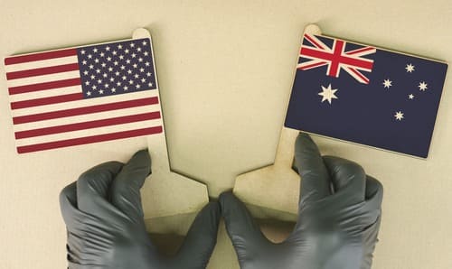 A worker's gloved hands holding cutout American and Australian flags together.