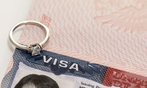 A closeup of a diamond engagement ring placed on top of a United States visa.