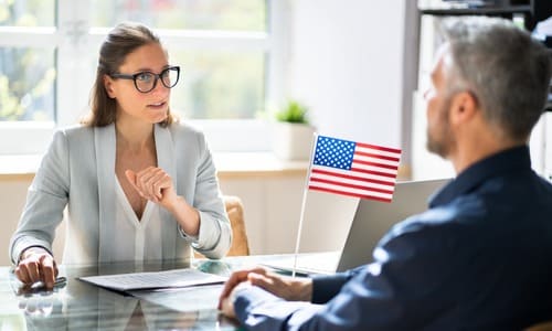 A female immigration bond attorney speaking with a client and with an American flag propped up on her desk.