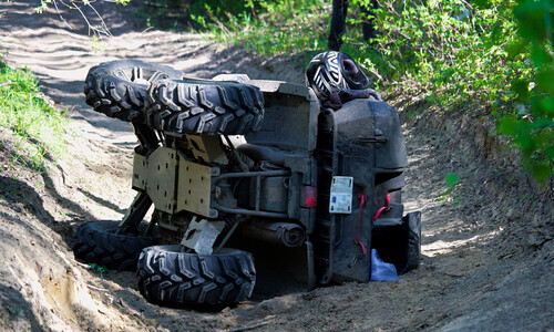 ATV turned on its side on a forest trail after an accident.