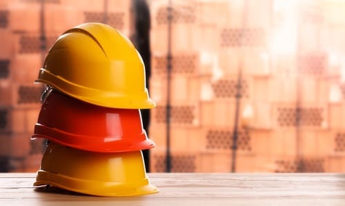 Stacked hard hats on a table at a construction site.