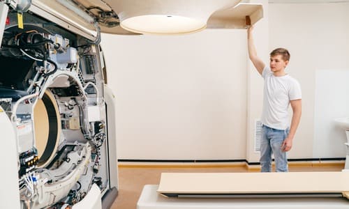 Engineer holding open the cover of an MRI machine to troubleshoot it.