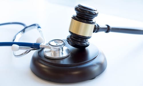 A gavel and a stethoscope side by side on a table.