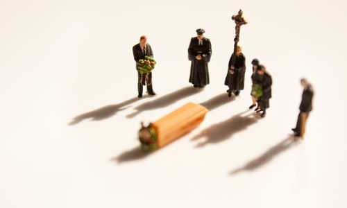 Model figures on a table arranged in a funeral setting with a family grieving over a coffin.