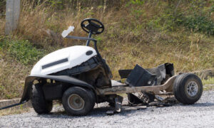Crashed golf cart sitting on the path after a serious accident.