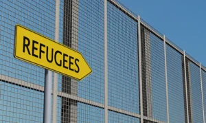 Yellow directional sign with the label "Refugees"