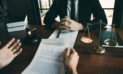 A lawyer seated at his desk advising his client on how to pursue a personal injury lawsuit.