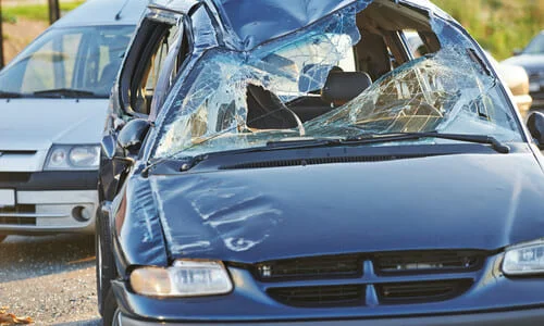 A black car with a smashed windshield after an accident with a van.