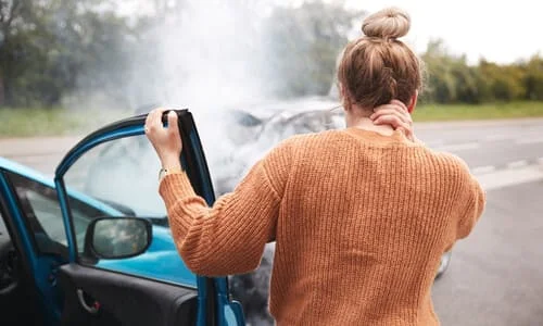 A woman stepping out of her car after a serious accident with another vehicle.