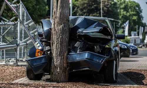 Front view of a dark blue automobile that crashed into a tree.