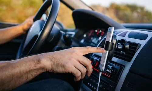 A rideshare driver inside his car getting ready to sign into his service application.