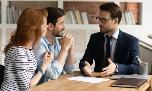 A couple in an office consulting with a lawyer regarding their legal options.