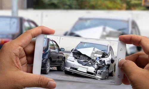 A first-person perspective shot of a person recording a car accident on their phone.