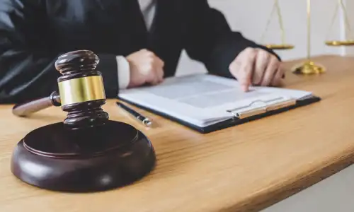 A personal injury lawyer reviewing a client's insurance policy documents on a clipboard on his desk.