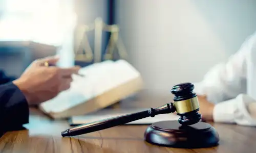 A lawyer and a client seating opposite each other at a desk while working on a personal injury case.