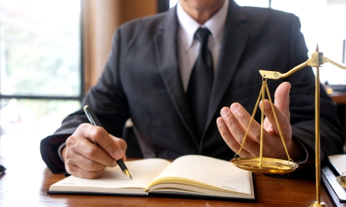 A Personal Injury Lawyer in their Lemoore office writing on a notebook.