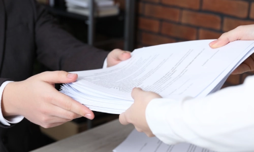 A Madera Acres personal injury lawyer is handing several legal documents and pieces of evidence to his client.