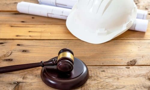 Workstation of a San Antonio construction site accident lawyer with a gavel hammer and a white safety hard hat placed on the wooden table.