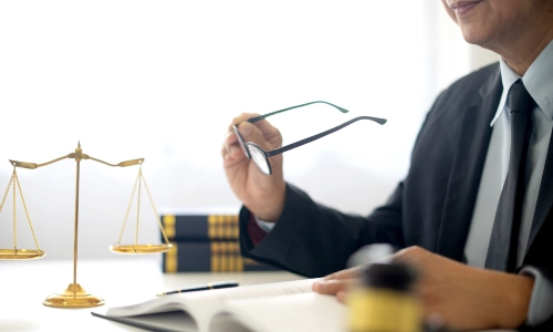 A San Antonio Defective Medical Device Lawyer holding a pair of glasses in the right hand and documents on the left hand.