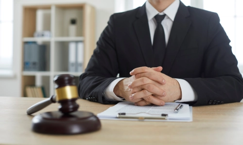 A Golf Cart Accident Lawyer sitting in a San Antonio Law office with both hands clasped on top of his office table.