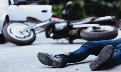 A male motorcycle accident victim lying on the street, appearing injured and in need of legal assistance from a San Antonio motorcycle accident lawyer.