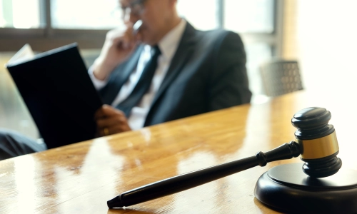 A Pedestrian Accident Lawyer seriously reading a case file with his right fist clenched and covering his mouth while sitting in a San Antonio office.