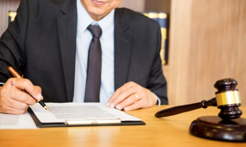 A close up of a Bret Harte Personal Injury Lawyer's hands as he reads through documents on a clipboard on his office desk.