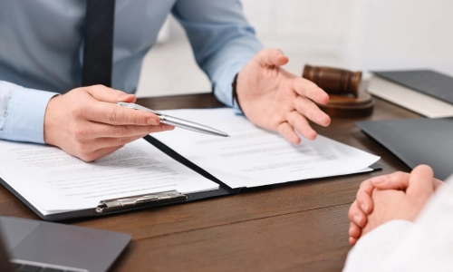 A Calwa Personal Injury Lawyer holding a silver pen in his right hand while explaining case details to a client who is sitting in front of him.