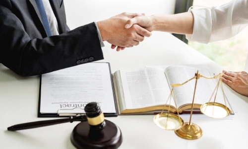 A Ceres Personal Injury Lawyer shaking the hand of a client sitting opposite of him on the table of the law office.