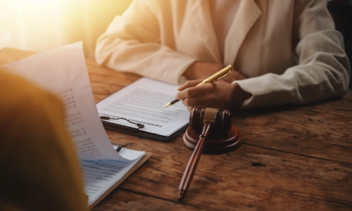 A Denair Personal Injury Lawyer holding a golden pen in her left hand while talking to a colleague sitting on the opposite side of the office table