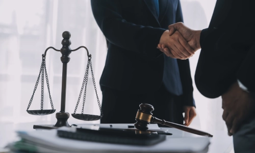 A Dos Palos Personal Injury Lawyer shaking the hand of a colleague while standing in front of them.