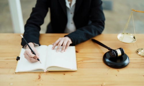 An East Bakersfield Personal Injury Lawyer sitting at a desk while writing on an open notebook