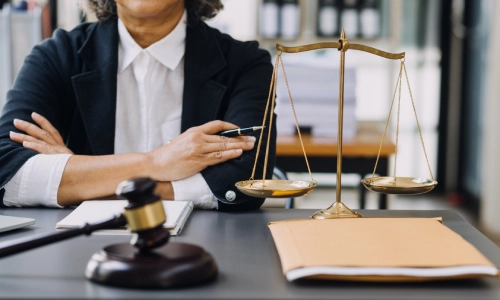 A female El Paso Robles Personal Injury Lawyer sitting with her arms crossed on top of an office table.