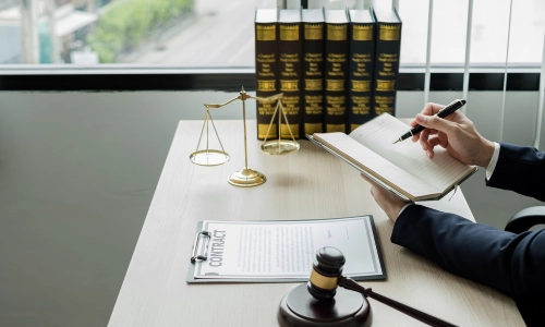 A Farmersville Personal Injury Lawyer holding a notebook while writing down notes on it while a contract lies on the table in front of him