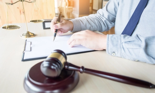 A Gilroy personal injury lawyer writing notes at his working desk with a gavel hammer placed beside him.