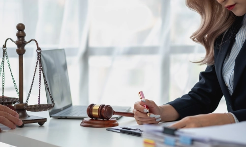 A female Gustine Personal Injury Lawyer reading files in her law office with a member of her legal team