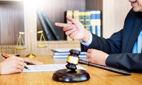 A Hanford Personal Injury Lawyer speaking to a client in his law office while the client signs some papers