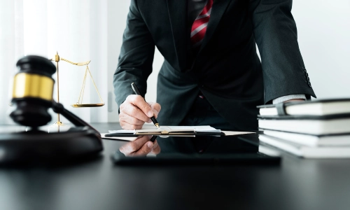 A Hughson Personal Injury Lawyer standing in his law office while leaning over a table and writing on a file.