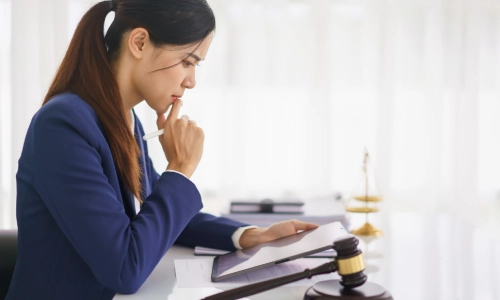 A female Ivanhoe Personal Injury Lawyer reviewing a case file while thinking