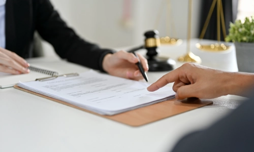An Oakdale personal injury lawyer writing notes while discussing the legal strategy they plan to pursue with their client.