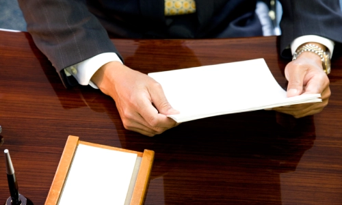 A close up shot of a Patterson Personal Injury Lawyer's hands holding files on top of their office table