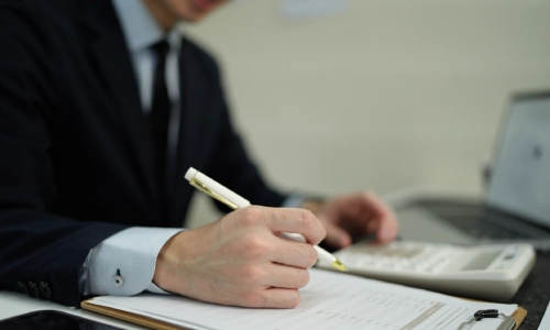 A Ridgemark Personal Injury Lawyer holding a white pen and writing notes on a document in his law office