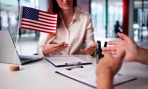A California EB-1C visa lawyer discussing a client’s visa application, with documents and a U.S. flag on the table.
