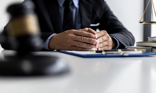 An underinsured motorist lawyer is sitting with both hands together on top of a document on a desk inside a California law office
