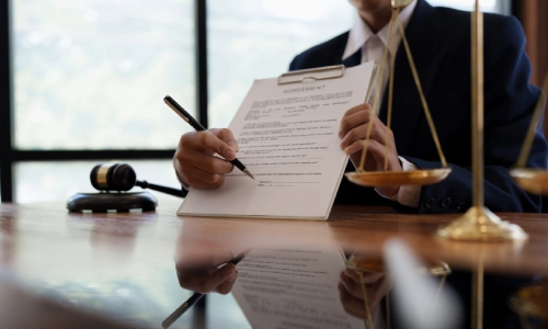 A California personal injury lawyer is holding up a contract in front of him while pointing to the signature section with a pen