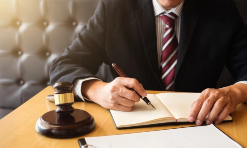 An uninsured motorist attorney serving California writes on an open notebook while a hammer and gavel are placed on the left side.