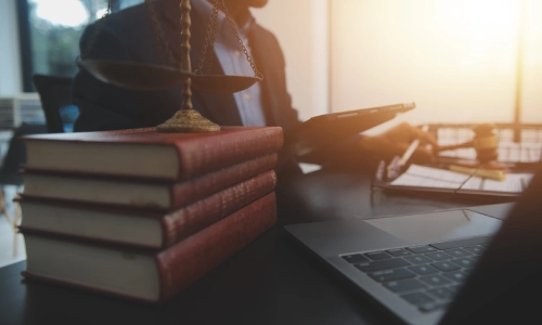 A close up shot of some books on an office desk with a slip and fall lawyer serving California sitting in the background while reading a document