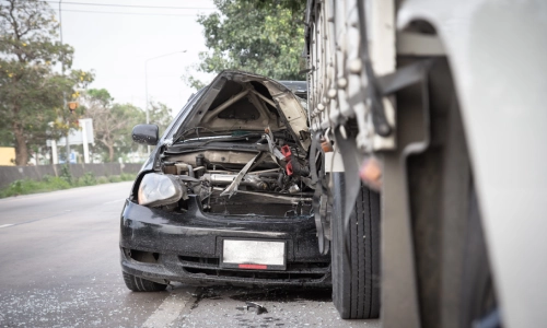 A scene of a California truck accident showing a car with a destroyed hood after hitting the back of a truck on the express way
