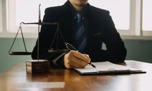 A California car accident lawyer signing a document attached to a clipboard while he sits inside a law office