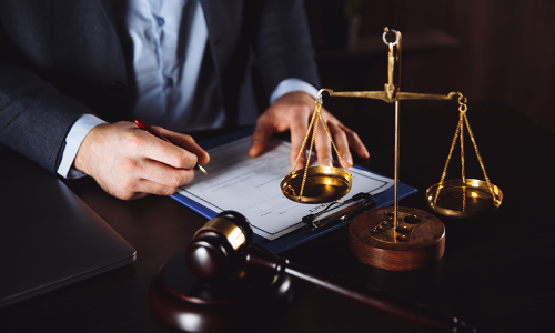 A California slip and fall lawyer signing legal documents while a balance scale stands in the foreground